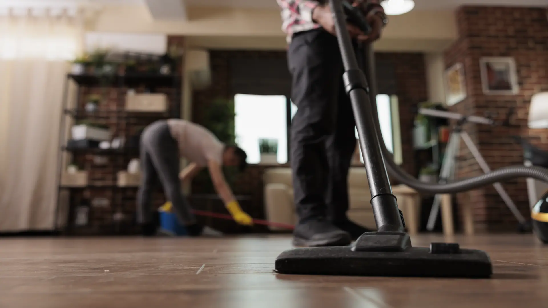 Man vacuuming floor while wife mops