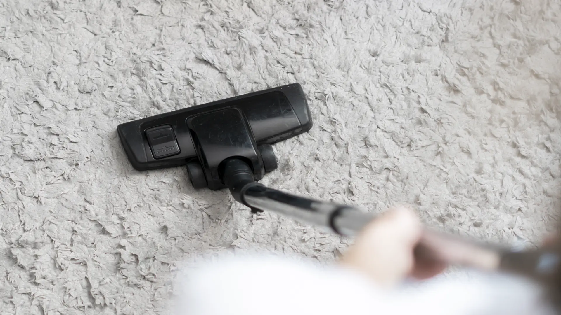 Person using vacuum cleaner on soft carpet