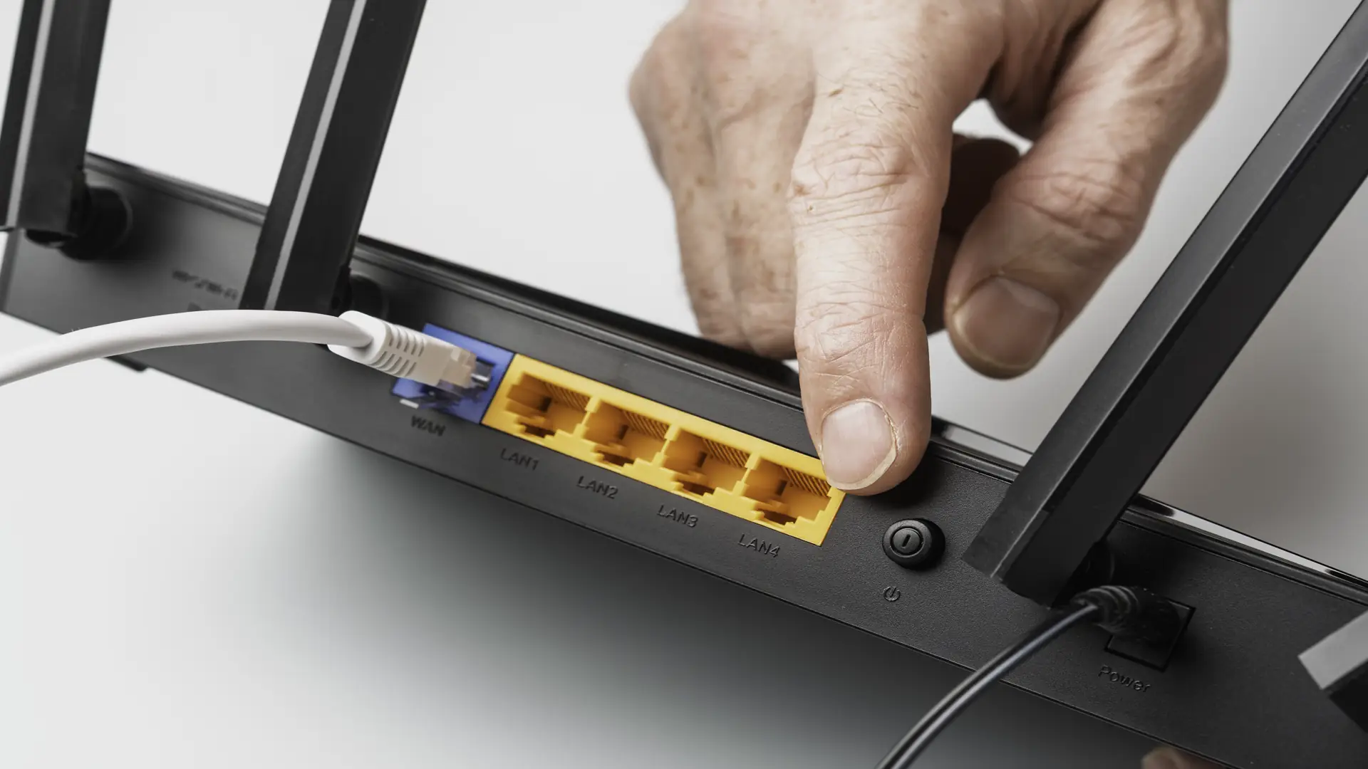 Male hand pressing power button on router