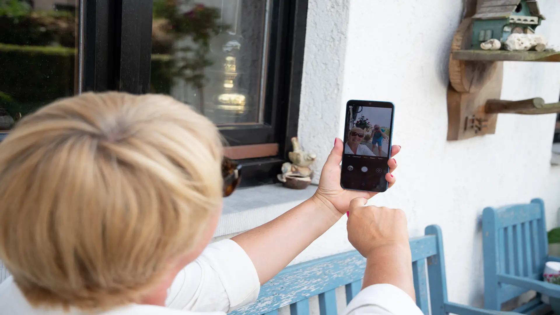 Woman with short blond hair smiling at video doorbell